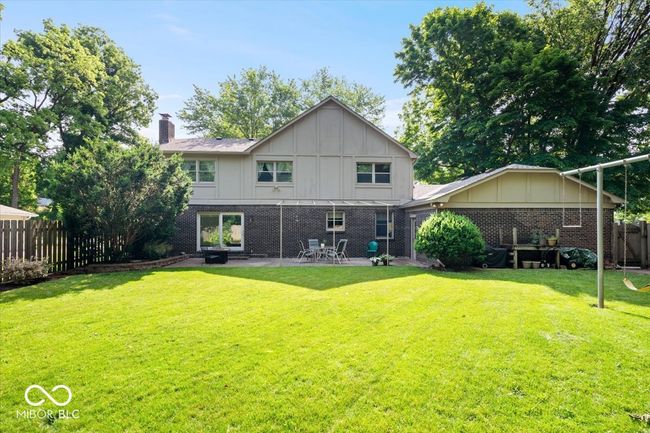 rear view of house with board and batten siding, a chimney, a patio area, and brick siding | Image 39