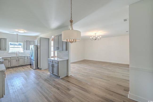 Kitchen with gray cabinets, freestanding refrigerator, a chandelier, tasteful backsplash, and light countertops | Image 11