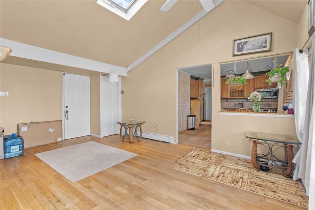 Foyer with baseboard heating, a skylight, high vaulted ceiling, and wood finished floors | Image 8