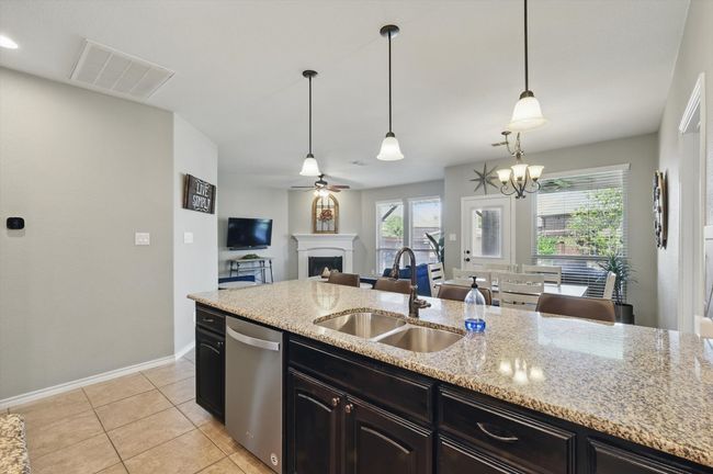 Kitchen featuring a fireplace, visible vents, dishwasher, a sink, and baseboards | Image 9