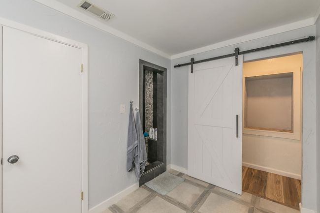 Unfurnished bedroom with a barn door and baseboards | Image 20