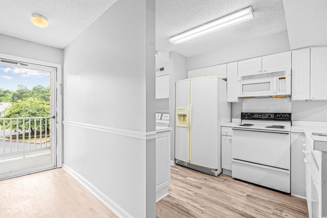 Kitchen with white appliances, a textured ceiling, light wood-style floors, white cabinetry, and light countertops | Image 6