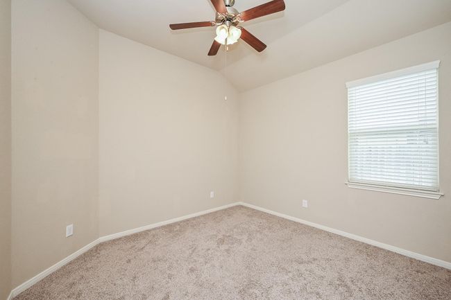 This bedroom #1 features carpet flooring with neutral walls, a ceiling fan with a light, and a window allowing natural light. | Image 8