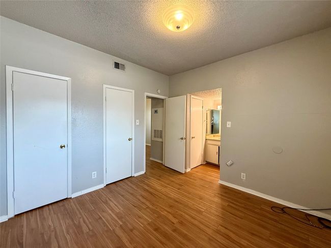Unfurnished bedroom with wood finished floors, a textured ceiling, and connected bathroom | Image 9