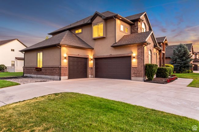Traditional home with stucco siding, concrete driveway, a front yard, a garage, and brick siding | Image 39