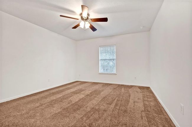 This room features a neutral color palette with carpeted flooring, a ceiling fan, and a single window allowing natural light. It's a blank canvas ready for personalization. | Image 24