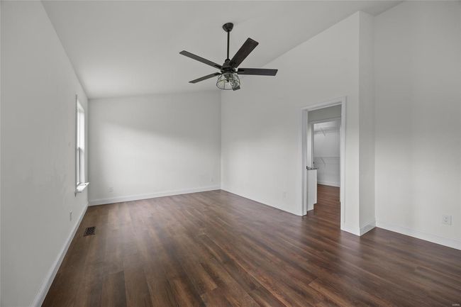 Empty room featuring ceiling fan, dark wood finished floors, baseboards, lofted ceiling, and visible vents | Image 37