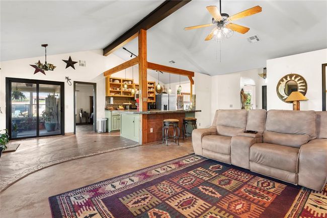 Living area with concrete floors, visible vents, ceiling fan, beam ceiling, and high vaulted ceiling | Image 12