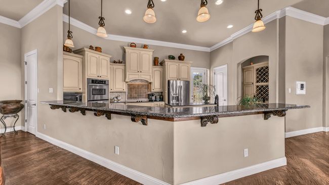 Kitchen with baseboards, a breakfast bar area, cream cabinets, backsplash, and stainless steel appliances | Image 11