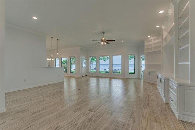 As you step inside, you're immediately welcomed by breathtaking panoramic views of Lake Conroe. The expansive living area has been fully remodeled, featuring wood-look tile flooring, custom built-ins, and wiring for surround sound, perfect for both relaxing and entertaining. | Image 8