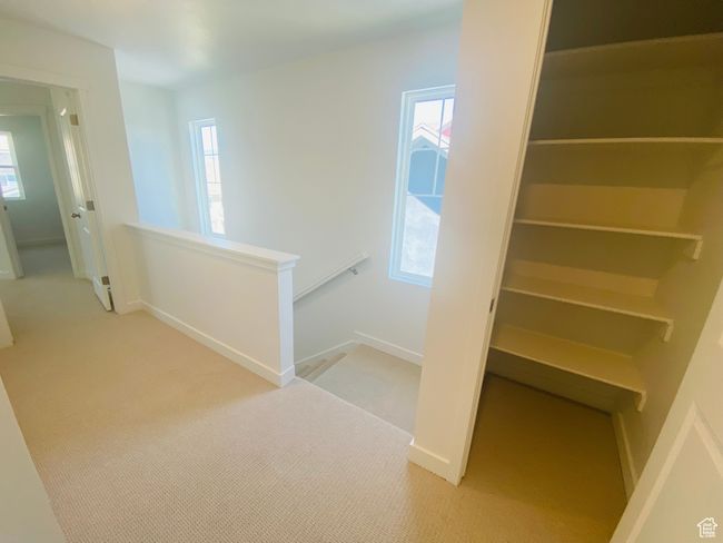 Hallway with an upstairs landing, light carpet, and healthy amount of natural light | Image 22