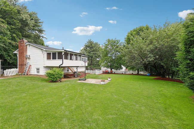 View of green lawn featuring a sunroom, stairs, and a patio | Image 33