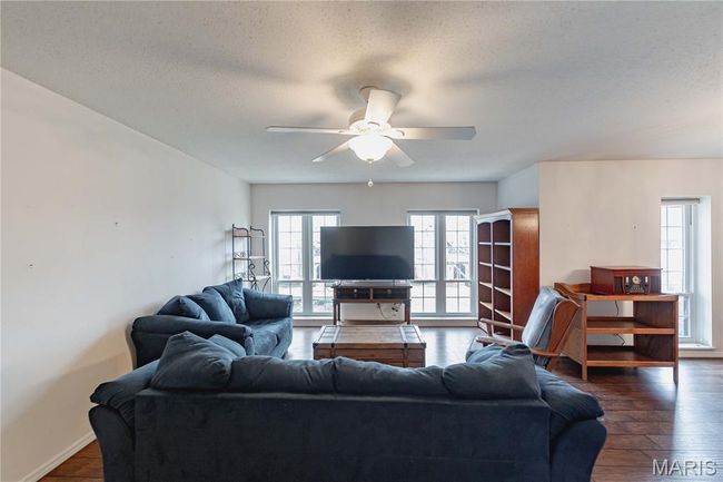 Living area with a ceiling fan, a textured ceiling, and dark wood-style flooring | Image 5