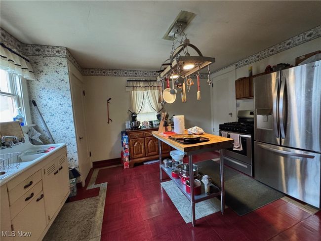 Kitchen with stainless steel appliances, a sink, baseboards, light countertops, and wallpapered walls | Image 4