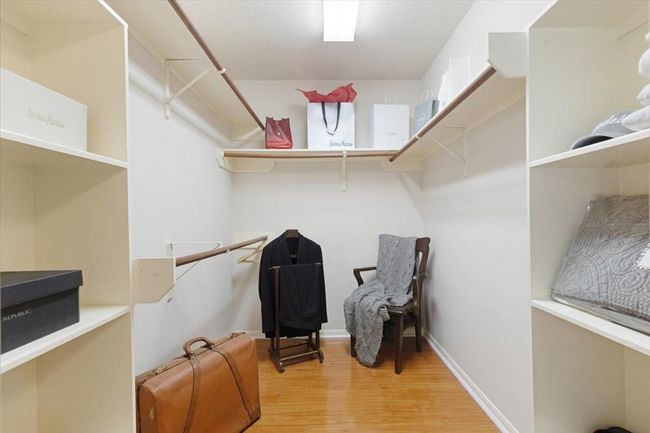 Spacious walk-in closet with wooden flooring, ample shelving, hanging rods, and bright lighting. Ideal for organized storage and easy access to clothing and accessories. | Image 19