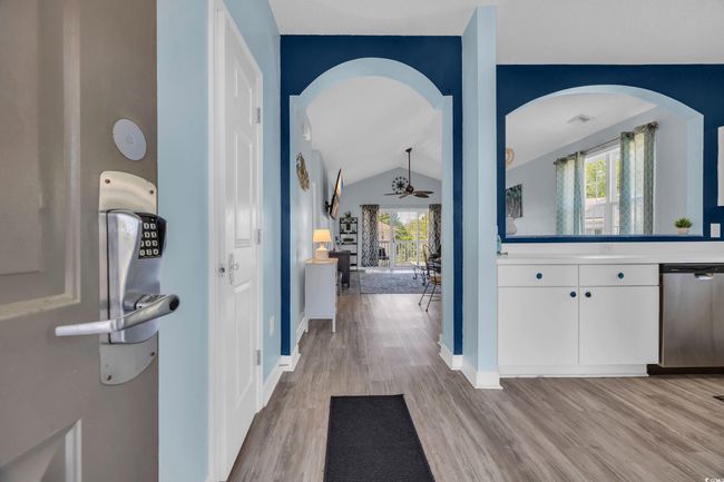 Hallway with light wood-type flooring, plenty of natural light, vaulted ceiling, and baseboards | Image 6