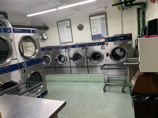 Shared laundry room with washer and dryer, concrete block wall, and stacked washer and clothes dryer | Image 11