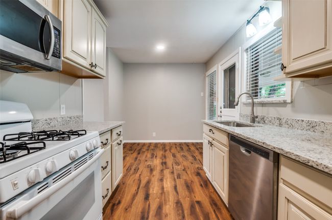 Kitchen with appliances, shelves, light wood-look flooring, and light stone counters | Image 14
