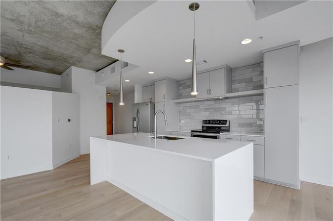 Kitchen featuring a sink, light countertops, light wood-style floors, and appliances with stainless steel finishes | Image 5