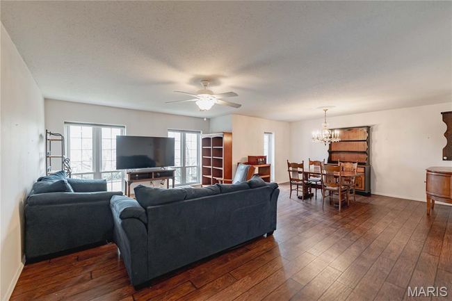 Living room with a ceiling fan, a chandelier, and dark wood-type flooring | Image 4