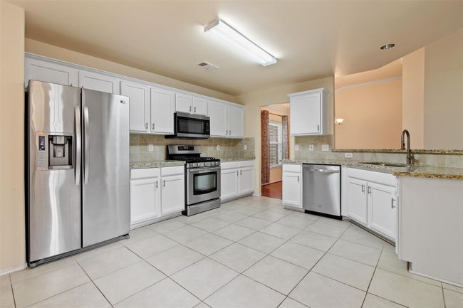 The updated kitchen has plenty of room for the chef in the family. It features granite countertops with tile backsplash and matching stainless steel appliances to include the gas range. Refrigerator is not staying unless it is purchased separately. | Image 10