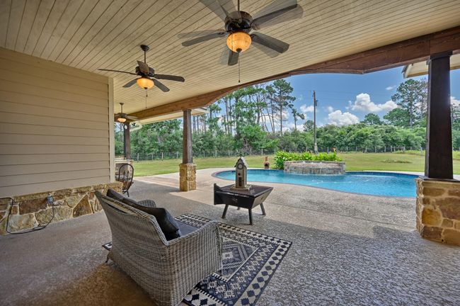 Roomy covered patio overlooking a serene pool, perfect for outdoor relaxation and entertaining. | Image 35