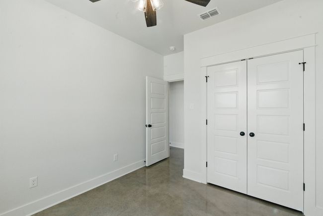 Unfurnished bedroom with finished concrete floors, baseboards, a closet, and ceiling fan | Image 17