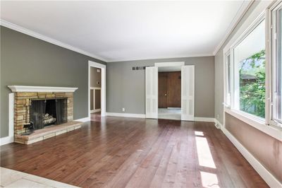 Unfurnished living room featuring ornamental molding, wood-type flooring, and a stone fireplace | Image 3