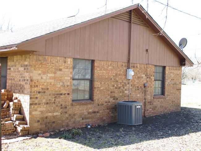 View of side of property with brick siding, roof with shingles, and cooling unit | Image 23