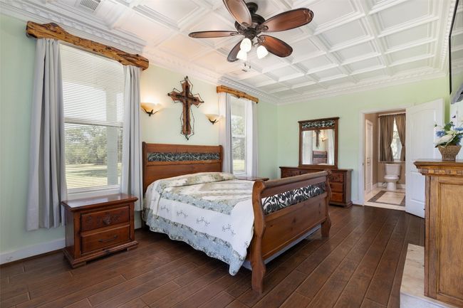 Bedroom with dark wood-style floors, an ornate ceiling, ceiling fan, and baseboards | Image 12