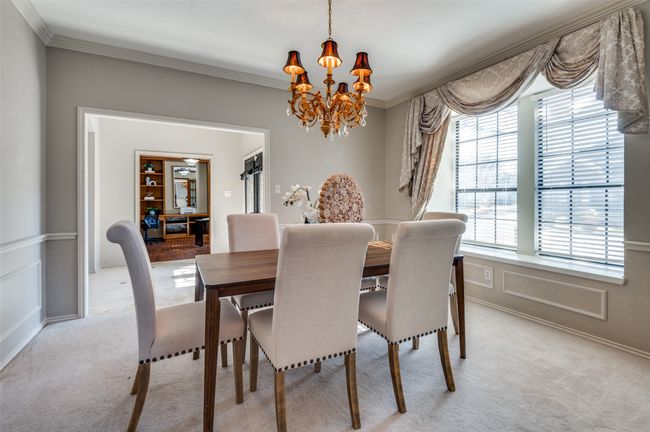 Dining area featuring crown molding, light colored carpet, a decorative wall, and a notable chandelier | Image 5