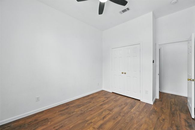 Unfurnished bedroom with wood finished floors, baseboards, a closet, and a ceiling fan | Image 9