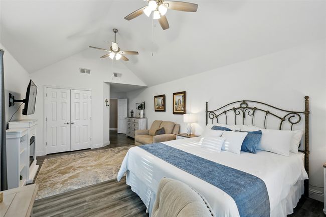 Large additnal primary second level ensuite bedroom with wood-like finished floors, a walk-in closet, ceiling fan, and high vaulted ceiling | Image 19