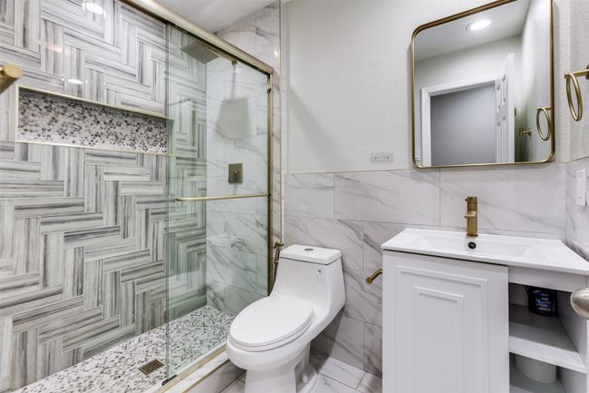 Full bath featuring tile walls, a shower stall, vanity, and a wainscoted wall | Image 18
