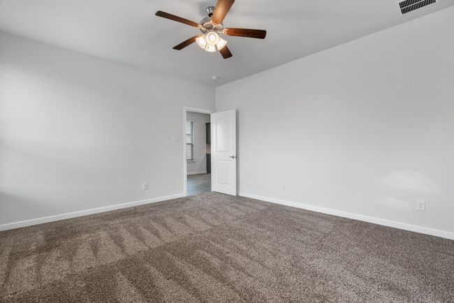 Spare room featuring carpet flooring, visible vents, baseboards, and ceiling fan | Image 16