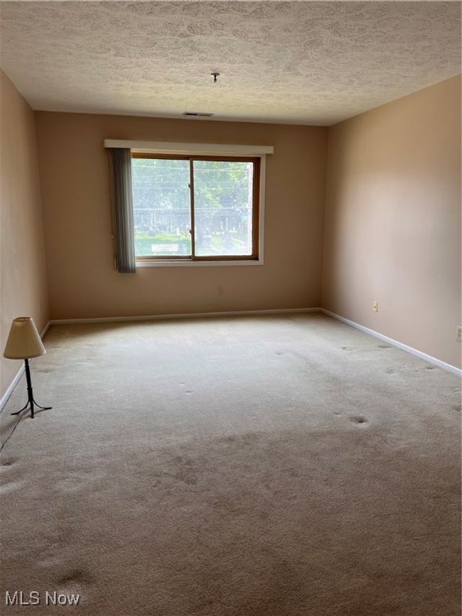 Primary bedroom featuring carpet flooring, a textured ceiling, and a pendent fire sprinkler | Image 7