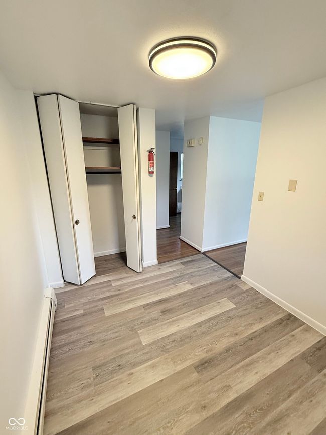 unfurnished bedroom with light wood finished floors, baseboard heating, and a closet | Image 8