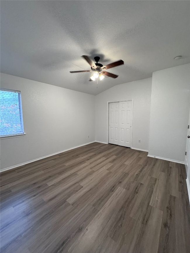 Unfurnished bedroom with dark wood finished floors, a textured ceiling, a closet, and ceiling fan | Image 30