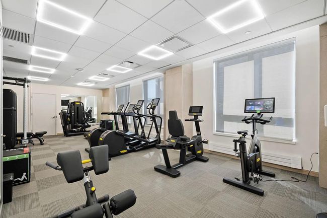 Workout area with a paneled ceiling and light colored carpet | Image 16