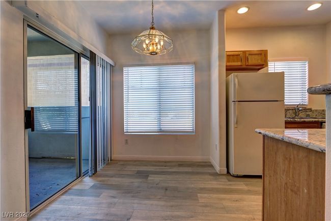 Kitchen featuring freestanding refrigerator, a chandelier, light wood-style flooring, light stone countertops, and a sink | Image 10