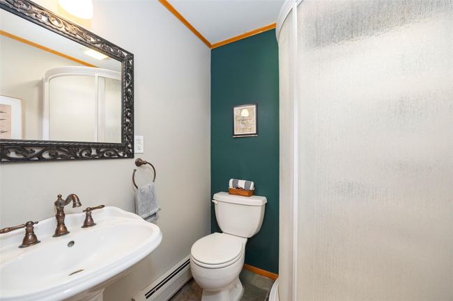 Bathroom with a baseboard radiator, a sink, crown molding, toilet, and a shower | Image 25