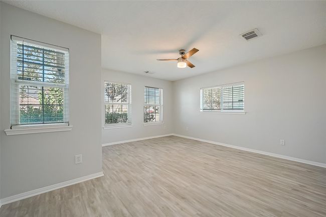 Large bedroom located in the front of the home. This room contains lots of natural light, luxury vinyl flooring and a modern ceiling fan. | Image 13