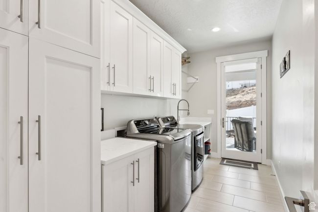 Laundry area with recessed lighting, cabinet space, light tile patterned flooring, separate washer and dryer, and baseboards | Image 22
