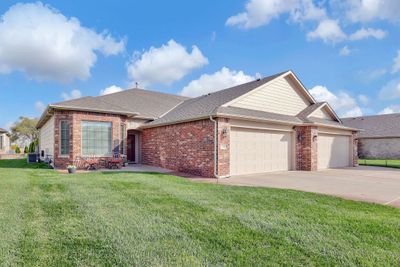 Ranch-style home featuring central air condition unit, a front yard, and a garage | Image 1