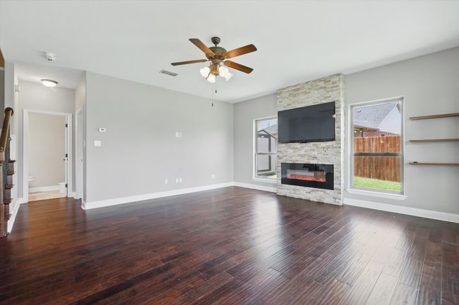 Unfurnished living room featuring healthy amount of natural light, a ceiling fan, a fireplace, and wood finished floors | Image 13