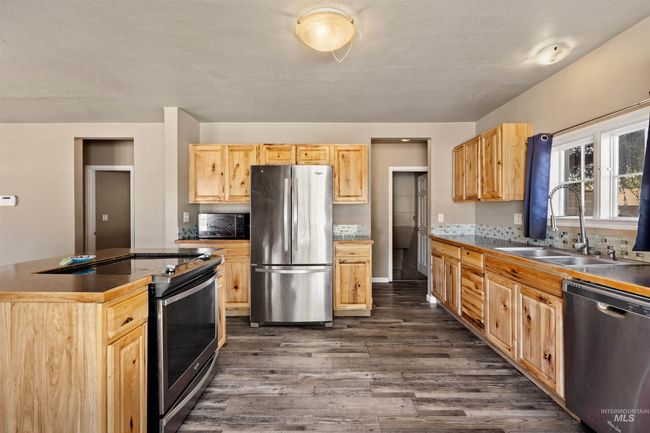 Kitchen with stainless steel appliances, dark wood finished floors, light brown cabinetry, and dark countertops | Image 16
