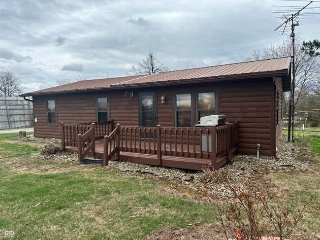 back of house featuring a lawn, metal roof, a deck, and log veneer siding | Image 6