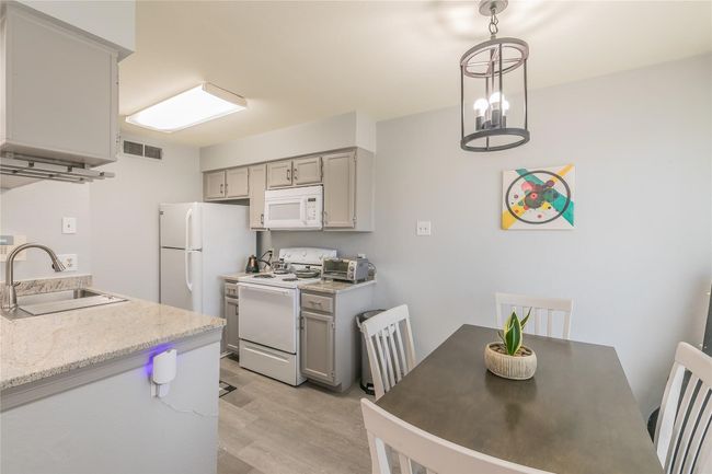 Kitchen with light hardwood / wood-style floors, gray cabinets, white appliances, pendant lighting, and sink | Image 4