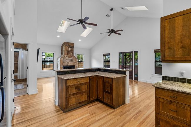 Kitchen with open floor plan, light wood-type flooring, a skylight, and high vaulted ceiling | Image 13
