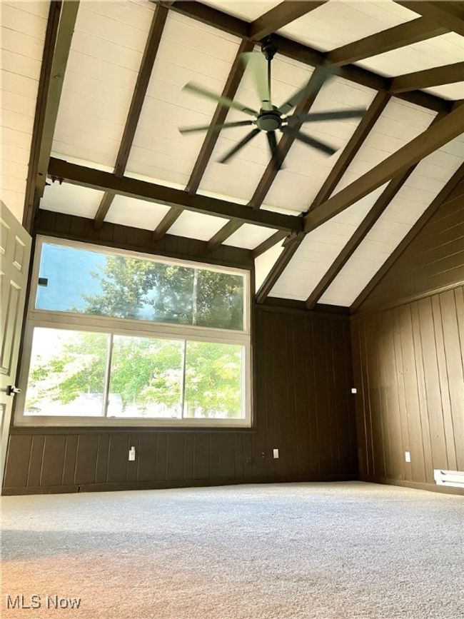Carpeted spare room featuring wooden walls and ceiling fan | Image 14
